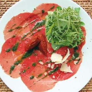 Rocket salad on Beef Carpaccio with pesto, hot pepper olive oil and Parmesan shavings - 